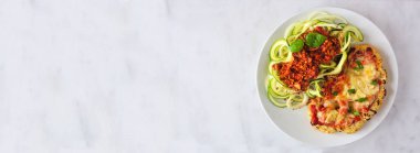 Karnabahar parmesan ve kabaklı makarna üzerine etsiz cevizsiz karnabahar bolonez. Beyaz mermer afiş arkaplanının üst görüntüsü. Sağlıklı beslenme, bitki temelli et ikame konsepti.