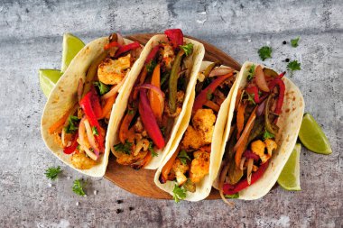 Izgara baharatlı karnabahar fajitası. Manzaranın üstünde taş bir arka plan var. Sağlıklı beslenme, bitki temelli et ikame konsepti.