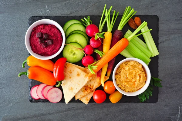 Sortiment Färska Grönsaker Och Hummus Doppa Serveringsfat Ovanstående Skiffer Bakgrund — Stockfoto