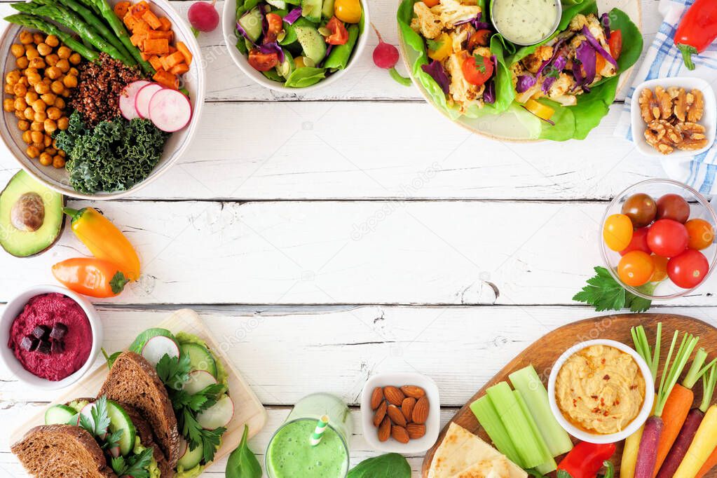 Healthy lunch food frame. Table scene with nutritious Buddha bowl, salad, lettuce wraps, vegetables and sandwiches. Top view over a white wood background. Copy space.