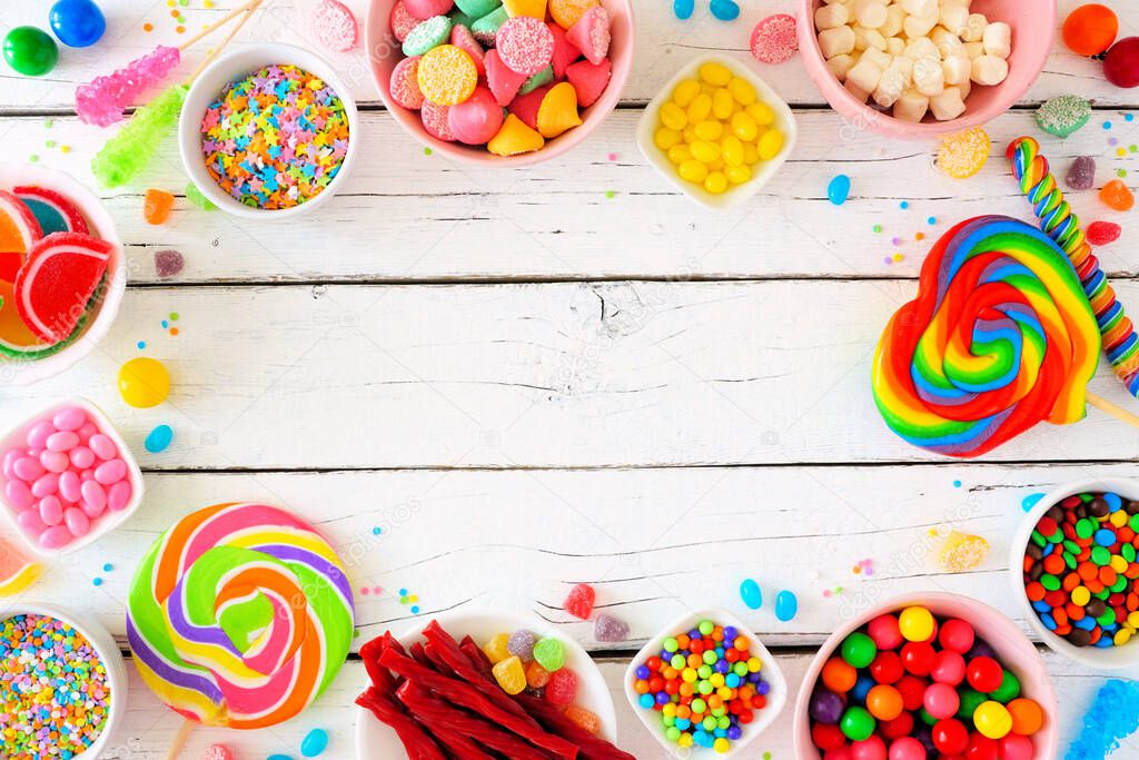 Sweet and colorful candy buffet frame. Above view table scene over a white wood background. Copy space.