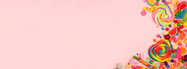 Renkli, çeşitli şekerler. Pembe afiş arkaplan üzerindeki üst görünüm kenarı.