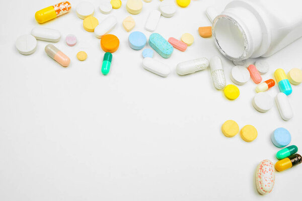 Medicine corner border with white bottle and spilling pills on a white background with copy space