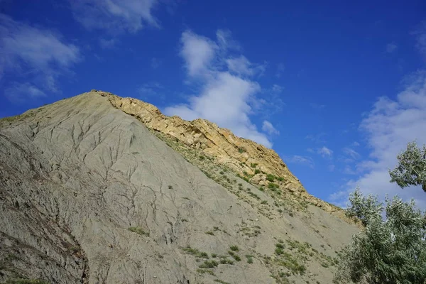 the hill of volcanic origin on the background of blue sky with white clouds in the Crimea