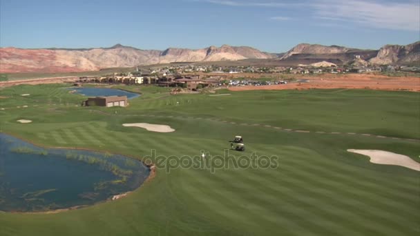 Aerial shot of golfers on desert course — Stock Video