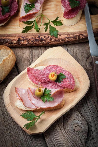 Tapas with sliced sausage, salami, olives and parsley. — Stock Photo, Image