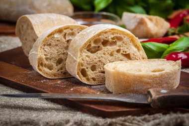 Ciabatta ekmeği kesme tahtası üzerinde dilimlenmiş.