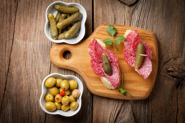 Tapas avec salami tranché, olives et concombre sur une table en bois . — Photo