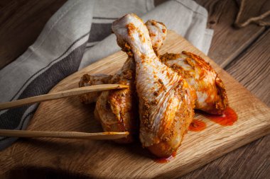 Ahşap doğrama tahtası üzerinde marine edilmiş tavuk sopaları.