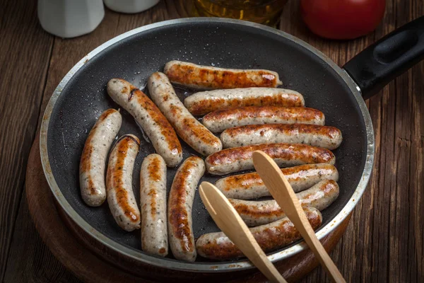 Fried white sausages in a cast iron skillet. — Stock Photo, Image