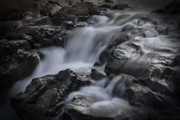 Rocks in stream with smooth flowing water. — Stock Photo, Image