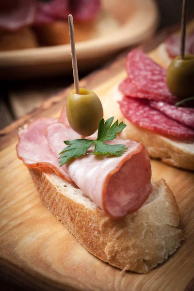 Tapas with sliced sausage, salami, olives and parsley. — Stock Photo, Image