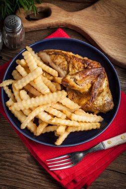 Bir tabak kızarmış patates ile kavrulmuş tavuk.