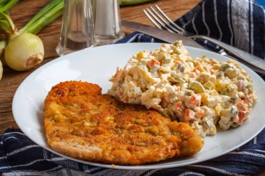 Fried pork chop in breadcrumbs, served with vegetable salad. clipart