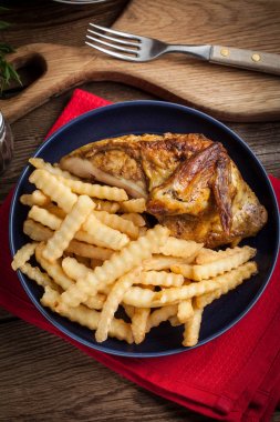 Bir tabak kızarmış patates ile kavrulmuş tavuk.