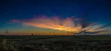 Gün batımında rüzgar türbinleri silueti.