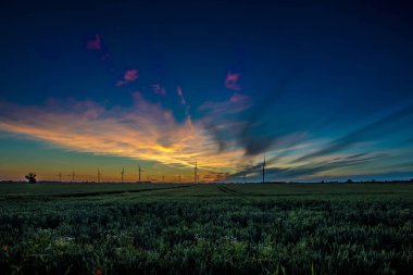 Gün batımında rüzgar türbinleri silueti.