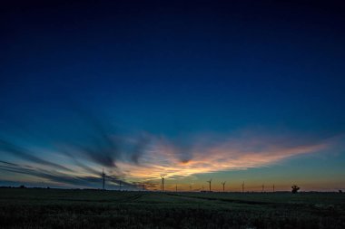 Gün batımında rüzgar türbinleri silueti.
