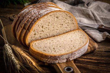 Bir kesme tahtası üzerinde ekmek dilimlenmiş. 