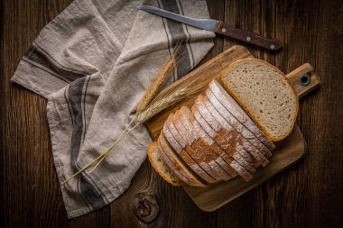 Bir kesme tahtası üzerinde ekmek dilimlenmiş. 