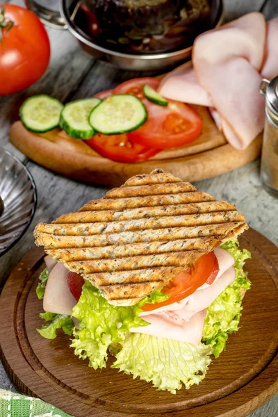 Сэндвич с ветчиной, огурцом, помидорами и салатом . — стоковое фото