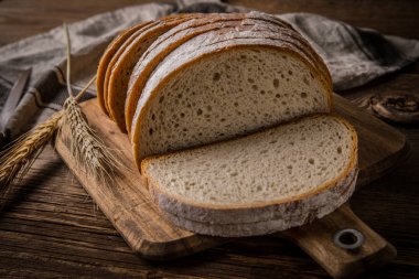 Bir kesme tahtası üzerinde ekmek dilimlenmiş. 