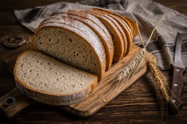 Bir kesme tahtası üzerinde ekmek dilimlenmiş. 