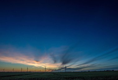 Gün batımında rüzgar türbinleri silueti.