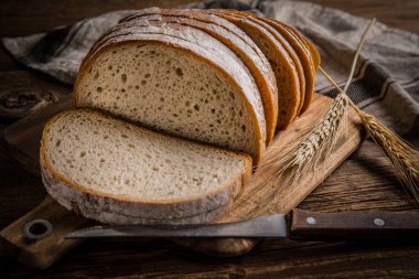 Bir kesme tahtası üzerinde ekmek dilimlenmiş. 