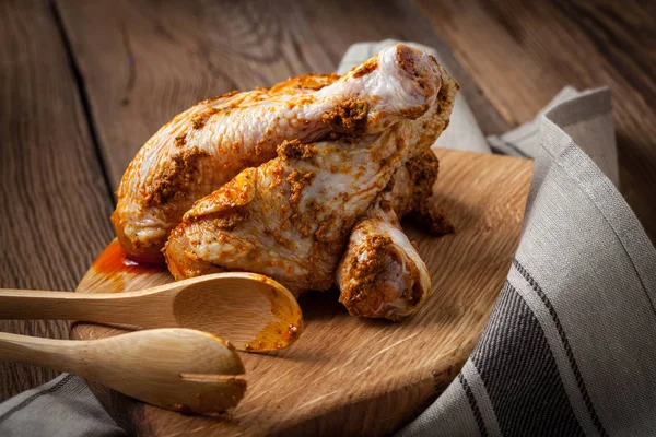 Marinated chicken drumsticks on a wooden chopping board. — Stock Photo, Image