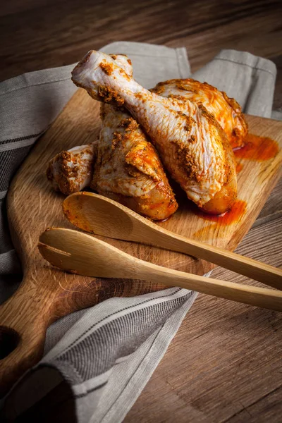 Marinated chicken drumsticks on a wooden chopping board. — Stock Photo, Image
