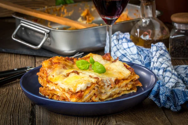 Pezzo di gustose lasagne calde con vino rosso. — Foto Stock