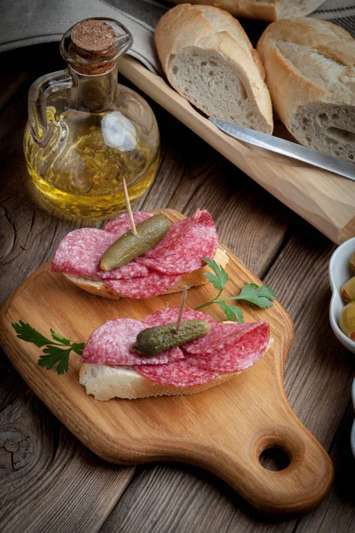 Tapas con salchichas en rodajas, salami, aceitunas y perejil . — Foto de Stock