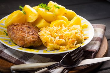 Patates ve lahana salatasıyla servis edilen kıymalı domuz pirzolası..