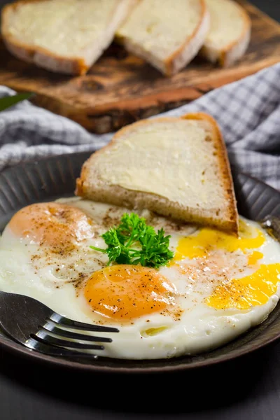 Gebakken eieren en brood voor het ontbijt op een grijze achtergrond. — Stockfoto