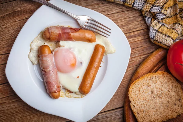 Fried eggs with sausages and bacon. — Stock Photo, Image