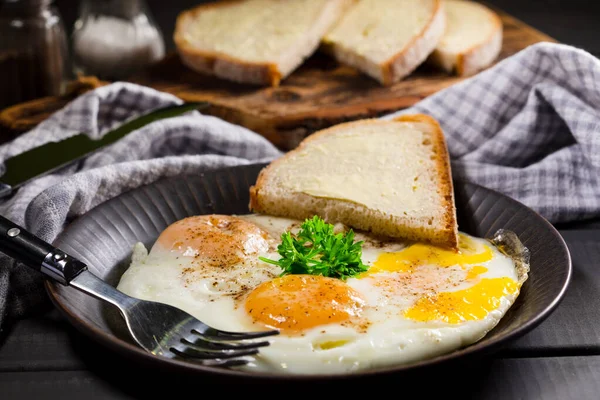 Gebakken eieren en brood voor het ontbijt op een grijze achtergrond. — Stockfoto