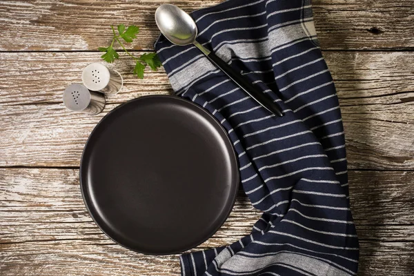 Black plate, spoon and napkin. — Stock Photo, Image