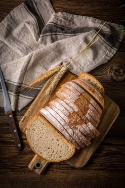 Bir kesme tahtası üzerinde ekmek dilimlenmiş. 