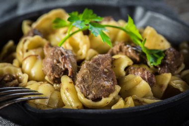 Biftek soslu İtalyan makarna kabukları dökme demir tavada..