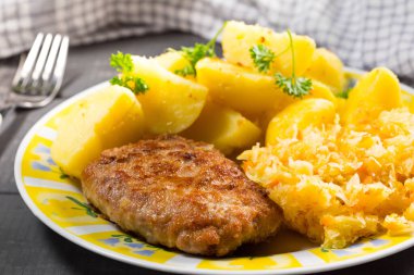 Patates ve lahana salatasıyla servis edilen kıymalı domuz pirzolası..