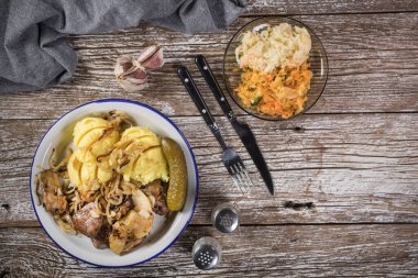 Kızarmış ciğer, soğan ve elma haşlanmış patates ve salatalık turşusu ile servis edilir. Üst görünüm.