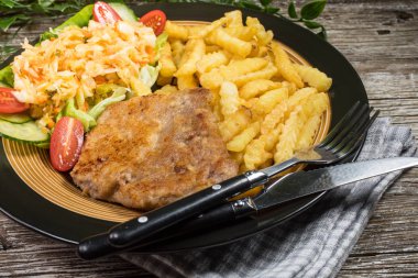 Geleneksel Polonya yemeği: kızarmış domuz pirzolası, patates kızartması ve salata ile servis edilir.. 