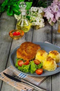 Pirzola, domuz jambonlu, haşlanmış patates ve tabakta salata..
