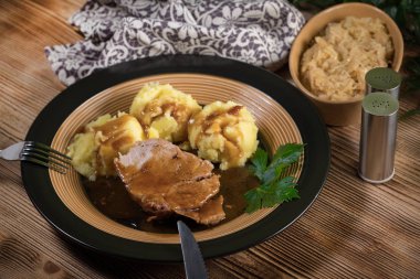 Kendi sosunda haşlanmış patates ve kızarmış lahanayla servis edilen haşlanmış domuz boynu. Sığ alan derinliği.