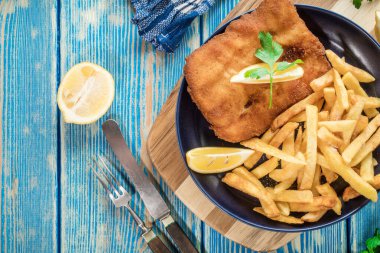 Tabakta patates kızartması olan kızarmış morina balığı. Üst görünüm.