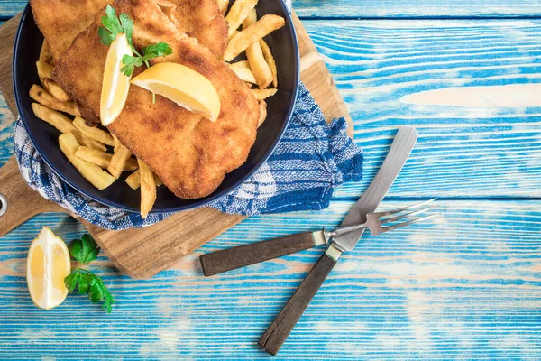 Tabakta patates kızartması olan kızarmış morina balığı. Üst görünüm.