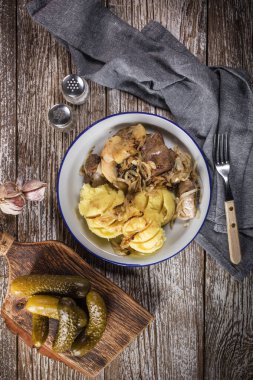 Kızarmış ciğer, soğan ve elma haşlanmış patates ve salatalık turşusu ile servis edilir. Üst görünüm.