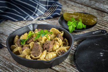 İtalyan makarna kabukları ve biftek sosu ahşap masada dökme demir tavada..