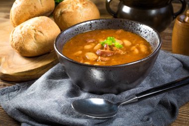 Domates soslu fasulye, pastırma ve siyah kasede sosis. Seçici odak.